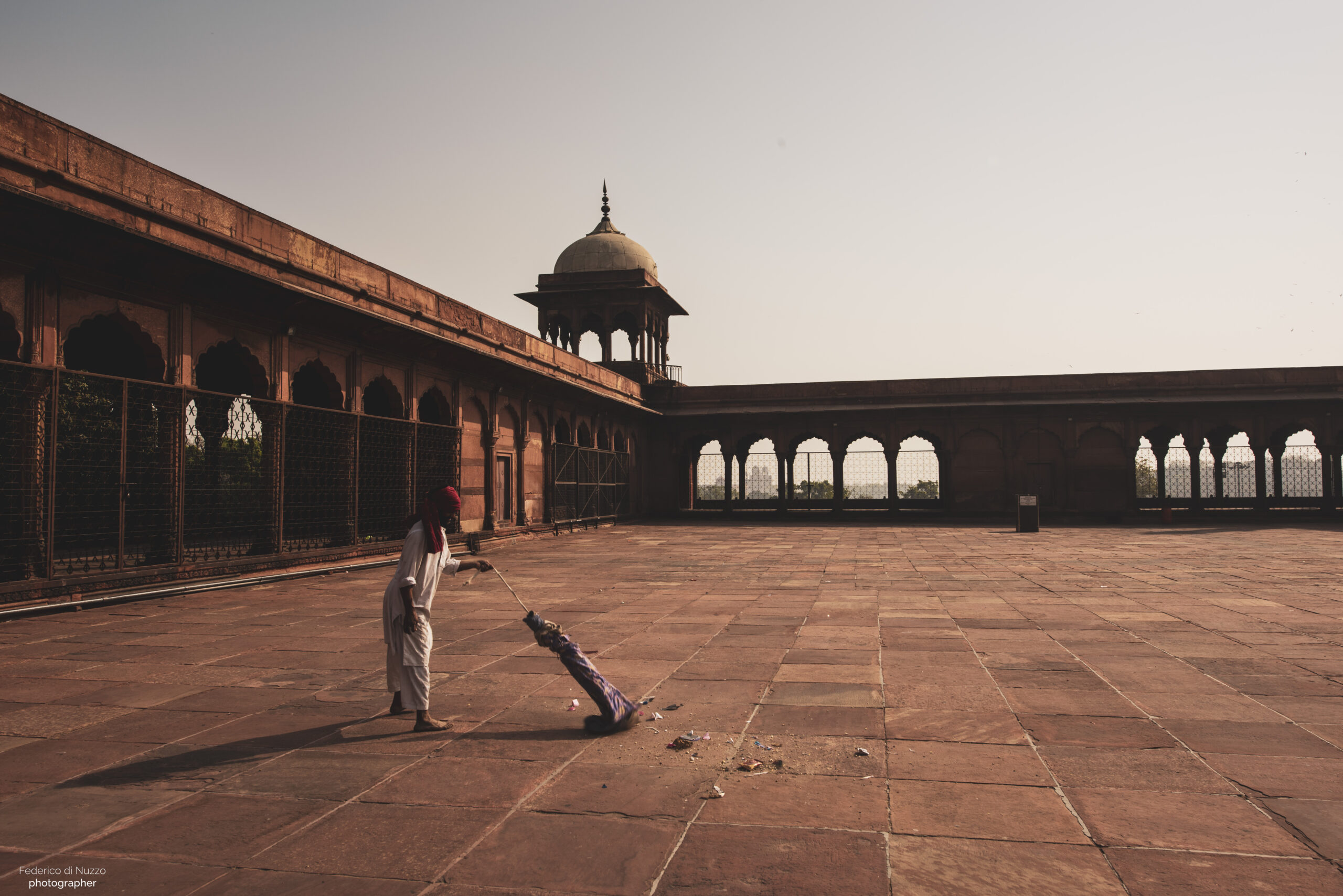 Inserviente che pulisce il pavimento della moschea Jama di Delhi